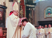  Arcybiskup Sławoj Leszek Głodź nakłada dłonie na głowę wyświęcanego diakona,  przekazując mu moc Ducha Świętego