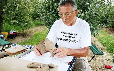 Marek Florek prezentuje odnalezione fragmenty naczyń sprzed kilku tysięcy lat