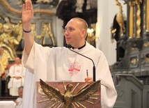 Przewodnik pielgrzymki ks. Rafał Babicki pokazuje pątniczą opaskę 