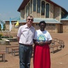 O. Andrzej Jakacki wraz z Nathalie – jedną z widzących – na tle kościoła w Kibeho