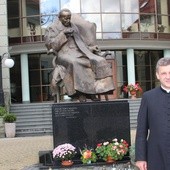 Biskup nominat Roman Pindel pod pomnikiem bł. Jana Pawła II na dziedzińcu kurii w Bielsku-Białej