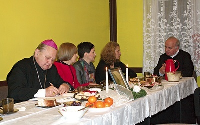   Biskup Gerard Kusz wpisuje się  do kroniki. Z prawej o. Jan Noga, duszpasterz amazonek