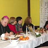   Biskup Gerard Kusz wpisuje się  do kroniki. Z prawej o. Jan Noga, duszpasterz amazonek
