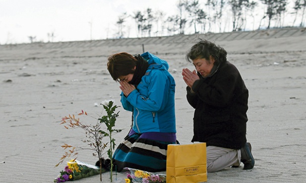 11.03.2014. Japonia. Kunie Konno i jej matka Kazue na plaży w Sendai modlą się za ofiary trzęsienia ziemi i tsunami, które nawiedziły Japonię 11 marca 2011 r. Zginęło wówczas 15 884 ludzi. 2636 osób  nadal uważa się za zaginione.