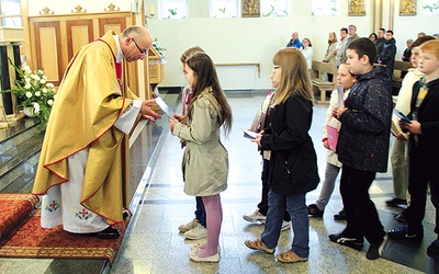  Proboszcz ks. Adam Domański przyjmuje w darze od dzieci zeszyty do religii