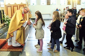  Proboszcz ks. Adam Domański przyjmuje w darze od dzieci zeszyty do religii