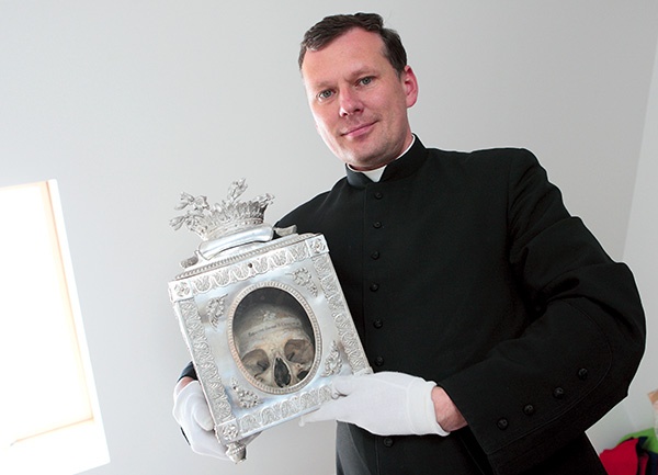 Ks. Marek Wojnarowski pokazuje czaszkę towarzyszki św. Urszuli. Relikwiarze będzie można oglądać w ramach podziemnej wystawy