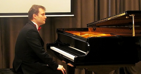Piotr Latoszyński przy fortepianie w pałacowej sali koncertowej