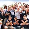 Młodzi wraz z profesjonalnymi aktorami w koszulkach promujących wydarzenie pokazują znak „X”, czyli „exodus” 
