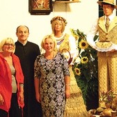  Magdalena Stancu i Halina Jach z ks. Wiesławem Kaniugą na tle dożynkowej dekoracji