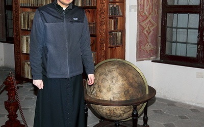 Ks. Sebastian Kazimirski prezentuje globus kosmosu z klasztornej biblioteki