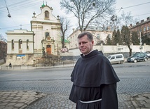 O. dr Stanisław Kawa przed kościołem św. Antoniego, za drzewami budynek  b. klasztoru, o który toczy się spór 