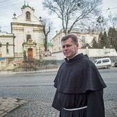 O. dr Stanisław Kawa przed kościołem św. Antoniego, za drzewami budynek  b. klasztoru, o który toczy się spór 