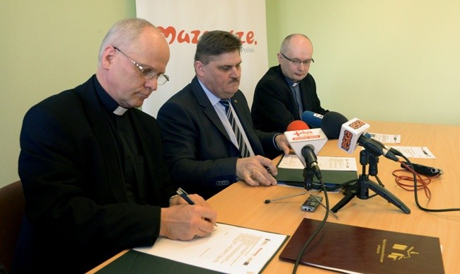 Stosowne dokumenty podpisują (od lewej): ks. Jarosław Wojtkun i Leszek Ruszczyk. Z prawej ks. Mariusz Wincewicz