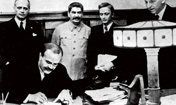 Wiaczesław Mołotow składa podpis pod paktem o nieagresji pomiędzy Związkiem Sowieckim a Trzecią Rzeszą. Joachim von Ribbentrop stoi za nim, obok Stalina