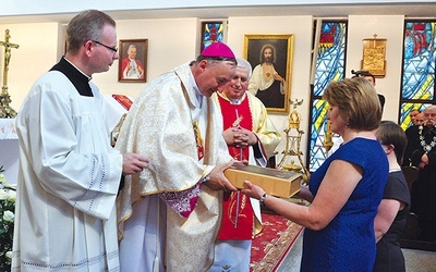 Parafianie składają w darze ołtarza pustą księgę na zapisywanie nowych łask wyproszonych przez Maryję
