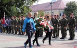 Delegacja uczniów niesie wiązankę kwiatów pod pomnik na pl. Kościuszki