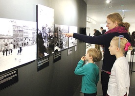  Najmłodsi patrzą na zdjęcia zbombardowanej Warszawy z niedowierzaniem