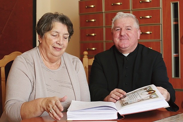  Ks. prał. Stanisław Morawa i Maria Satława nad kroniką parafii rozmawiają o nadchodzącym wydarzeniu 