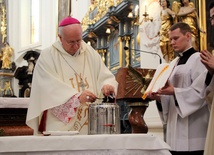 Bp Andrzej F. Dziuba wlewa wonny balsam do naczynia z olejem