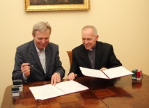 Krzysztof Terka i ks. Bogumił Karp podpisują umowę o remoncie parafialnego kompleksu