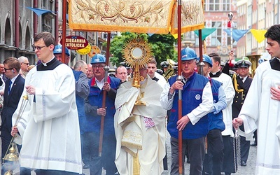 Abp Sławoj Leszek Głódź niesie Najświętszy Sakrament podczas procesji.