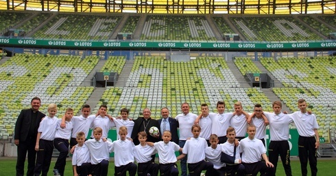 Pamiątkowe zdjęcie młodych piłkarzy z abp. Sławojem Leszkiem Głódziem na stadionie Energa