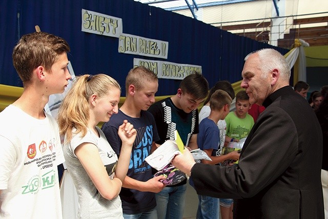 	Ks. Bolesław Kuśmirek wręcza upominki gimnazjalistom zaangażowanym w projekt edukacyjny o Janie Pawle II.