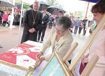 Danuta Ciesielska symbolicznie wbija gwóźdź w drzewce sztandaru szkoły.