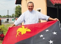 Bp Dariusz Kałuża z flagą Papui-Nowej Gwinei przed domem w Mizerowie pod Pszczyną