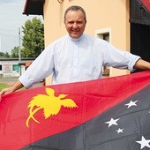 Bp Dariusz Kałuża z flagą Papui-Nowej Gwinei przed domem w Mizerowie pod Pszczyną