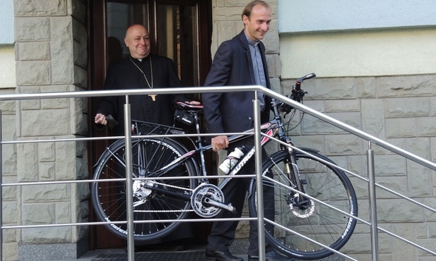 Ks. Grzegorz Kierpiec wyprowadza rower biskupa P. Gregera na dziedziniec kurii
