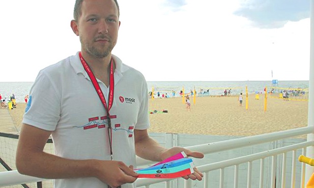 Mateusz Żylewicz pokazuje darmowe opaski, które można otrzymać od ratowników na gdańskich plażach.