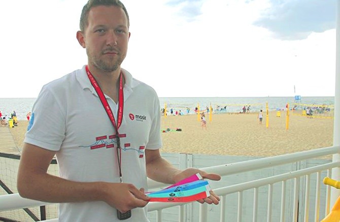 Mateusz Żylewicz pokazuje darmowe opaski, które można otrzymać od ratowników na gdańskich plażach.