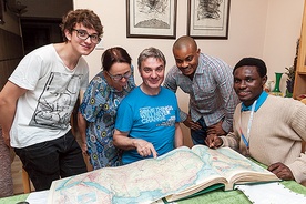 Rodzina państwa Gruców wraz z synem Marcinem i ich gośćmi z Nigerii oglądają mapę kraju w starym atlasie.