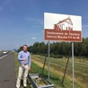 Senator Przemysław Błaszczyk przy znaku turystycznym na autostradzie A2