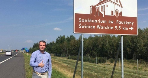 Senator Przemysław Błaszczyk przy znaku turystycznym na autostradzie A2