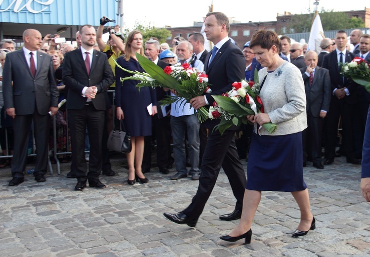 A. Duda i B. Szydło składają kwiaty pod bramą nr 2