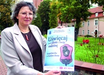 	Joanna Olbert, prezes DIAK AG, prezentuje plakat promujący inicjatywę „Uświęcaj swój dom i swoją rodzinę”.