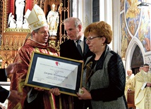 Nagrodę „Viventi Caritate” za rok 2016 z rąk bp. Henryka Tomasika odbiera Lucyna Wiśniewska. W środku Zbigniew Miazga.