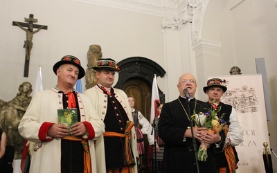 Bp Józef Zawitkowski w otoczeniu mężczyzn w strojach łowickich