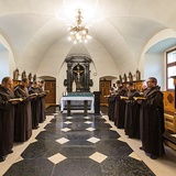 Karmelici odmawiają brewiarz w chórze  za ołtarzem.