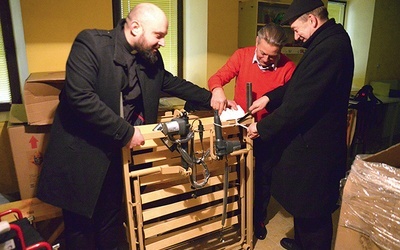 ▲	Rozpakowywanie specjalistycznego łóżka rehabilitacyjnego. Od lewej: ks. Damian Drabikowski,  Andrzej Reguła  i ks. Adam Płuciennik.