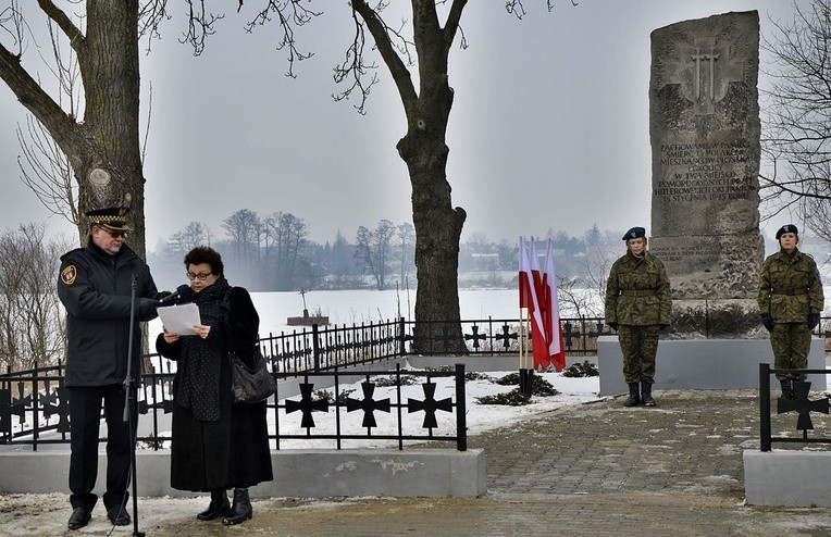 O hitlerowskiej zbrodni mówiła Mirosława Krysiak. W oddali, widoczne miejsce faktycznego mordu: z przekrzywionym krzyżem