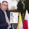 Ks. Mariusz Wilk z dyplomem potwierdzającym przyznanie nagrody wojewódzkiej.