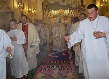 Bp Józef Zawitkowski niesie Najświętszy Sakrament po dywanie z kwiatów w kościele oo. pasjonistów w Rawie Mazowieckiej