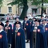 Mężczyźni w reprezentacyjnych strojach bractwa podczas procesji eucharystycznej.