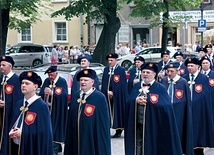 Mężczyźni w reprezentacyjnych strojach bractwa podczas procesji eucharystycznej.