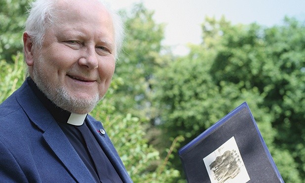 Ks. Ireneusz Mroczkowski przegląda album ze zdjęciami z czasów pobytu w wojsku. Wraz z nim przebywali tam m.in. ks. Henryk Lipka i ks. Wojciech Marszał.