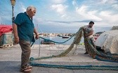 Stary Miguele razem z wnukiem naprawia sieć przed wypłynięciem na połów. Zawód rybaka przechodzi z ojca na syna.